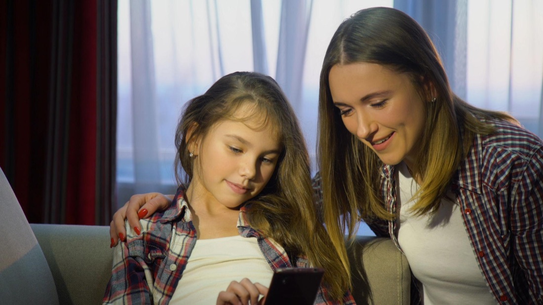 Responsável e criança usando celular para registro diário
